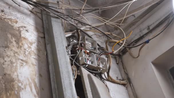 很古老的插头和电缆挂在天花板上 翻新房屋 更换旧的低质量电线 电线接错了从老房子的白墙伸出的电缆 — 图库视频影像