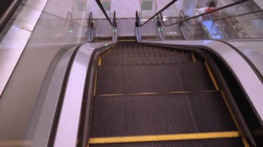 Yukarı doğru giden boş merdivenleri yakın plan çekiyoruz ve bir süre sonra duruyoruz. Modern yürüyen merdiven, kapalı alanda hareket eder..