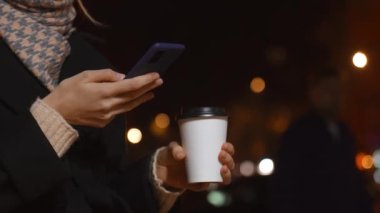 Şehrin caddelerinde kahve içerken cep telefonunu kullanan genç bir kadının elleri. Kahve dükkanı ve kahve servisi. Şehirde gezer..