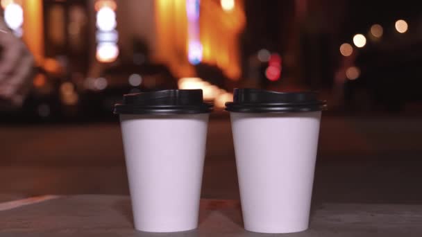 Şehir Işıklarının Bulanık Arka Planında Tek Kullanımlık Iki Beyaz Bardak — Stok video