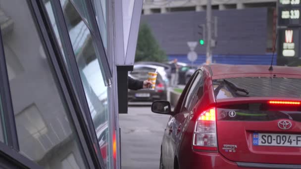 ジョージア州Batumi January 2024 ファーストフードレストランを通じてコーヒーや食べ物を手に入れる車の女性 配達窓の運転者のためのテイクアウトの順序を提供するスタッフ マクドナルド ドライブ スルー — ストック動画