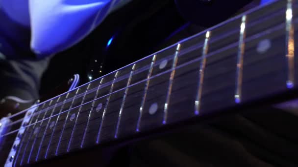 エレクトリックギターを演奏する男 情熱的なメロディーを巧みに作り上げる男の手のクローズアップ 弦やフレットに滑らかに動く指 ネオンブルーライト — ストック動画