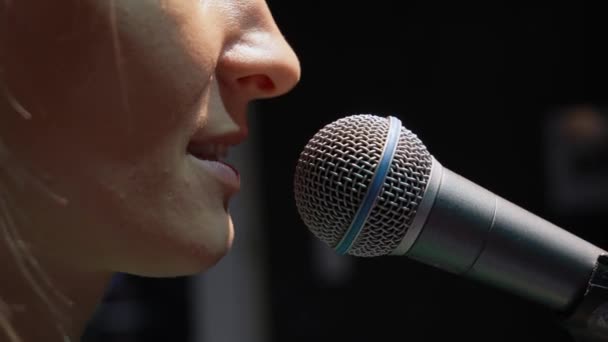 对着话筒唱歌或说话的妇女的嘴巴和嘴唇的特写 她站在黑色的背景上 嘴里衔着话筒 音乐会或录音室 — 图库视频影像