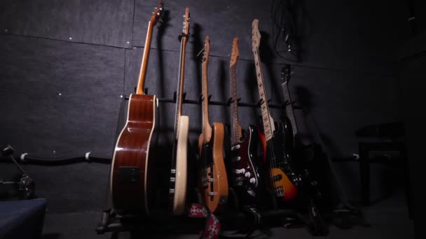 壁のホックや棚にエレガントに表示される多彩な色の音響ギターやベースギター レコーディングスタジオやコンサート モーションカメラ — ストック動画