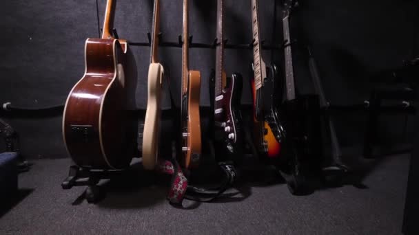 壁のホックや棚にエレガントに表示される多彩な色の音響ギターやベースギター レコーディングスタジオやコンサート モーションカメラ — ストック動画