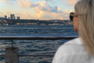 İstanbul 'daki İstanbul Boğazı ve Avrupa bölgesine bakan beyaz gömlekli güzel sarışın bir kadının portresi, seçici bir odak noktası..