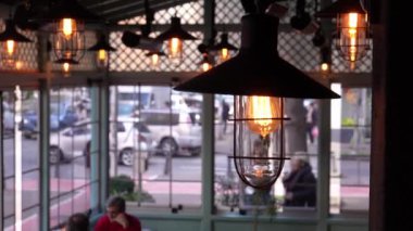 Kafenin içinde, tuğla duvar arkasında Edison tarzında parıldayan antika ampuller ve akkor ampuller var. Klasik lamba dekoratifi.