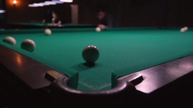 Rus bilardosu oynuyorum. Arka plandaki adam topa vuruyor, beyaz topu cebine atıyor. Rus bilardo masası yeşil, top cebe uçuyor. Başarı kavramı. Top delikte. Dava.