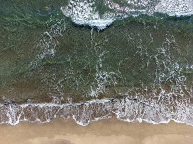Güneşli bir günde kumlu sahil ve deniz dalgalarının drone görüntüsü. Havadan gelen yaz deniz manzarası. Seyahat kavramı ve fikri