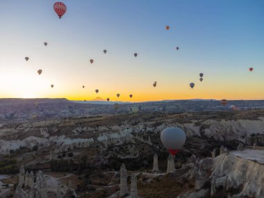 Nevsehir, Goreme, Kapadokya, Türkiye 'deki muhteşem bacalar vadisinde renkli balonlar uçuşuyor. Kapadokya 'daki bir drondan nefes kesici panoramik manzara, sıcak hava balonu turizmi..