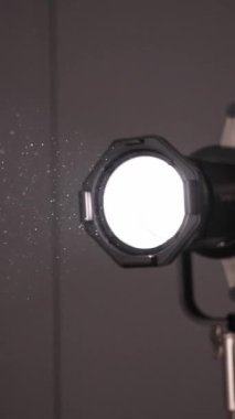 Sahne ışığından yansıyan ışık karanlık odayı aydınlatır. Toz parçacıkları lambadan gelen ışıkta yüzer ve parlar. İyileş. Soyut sinema arkaplanı. dikey video