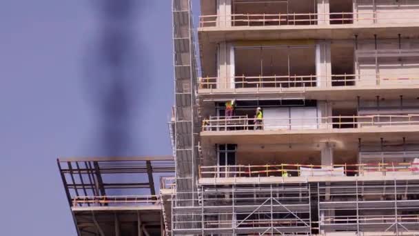 建物のファサードのクラッディングの壁を覆う労働者 エンジニアの建設コンセプトの下の家の壁および建築現場でデッサンで働く建築家 — ストック動画