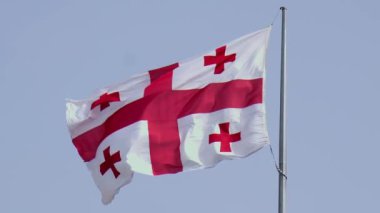 Gürcistan 'ın ulusal bayrağının yakın çekimi mavi gökyüzüne karşı kopyalanmış uzayla dalgalanıyor. Uluslararası ilişkiler kavramı. Gürcistan bayrağı açık, mavi gökyüzünün arka planında rüzgarda dalgalanıyor. Yavaş çekim