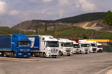 İstanbul, Türkiye - 7 Eylül 2023: Otoparkta dağların arka planına karşı çeşitli kamyonlar sıraya dizildi. Kargo taşımacılığı, lojistik kavramı