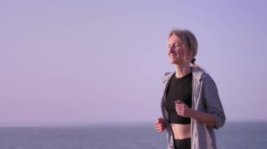 Fitness, spor ve sağlıklı yaşam tarzı konsepti - şehirde gülümseme ve yaz macerası ile deniz gezintisinde koşan genç kadın. Yolculukta mutlu ve genç. Özgürce koşan okyanus turu.
