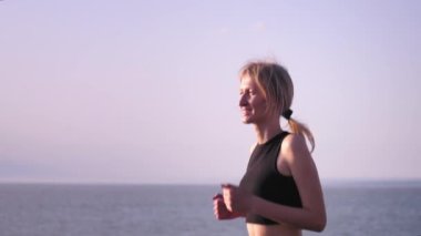 Fitness, spor ve sağlıklı yaşam tarzı konsepti - şehirde gülümseme ve yaz macerası ile deniz gezintisinde koşan genç kadın. Yolculukta mutlu ve genç. Özgürce koşan okyanus turu.