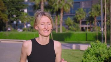 Genç, gülümseyen, sportif bir kadın sabah parkta koşarken palmiye ağaçlarının arka planında. - Evet. Spor salonundaki koşan kız Aktif Spor Kafkasyalı Kadın Sabah Egzersizi