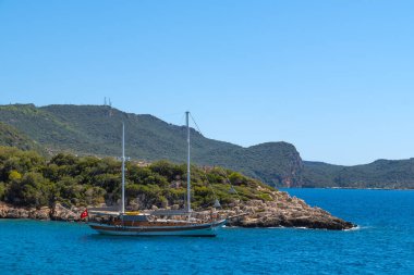 Parlak güneşli bir günde Akdeniz kıyısında turkuaz bir denizde yelken direkleri olan güzel bir yatın yakın çekimi. Seyahat, turizm, tatil kavramı