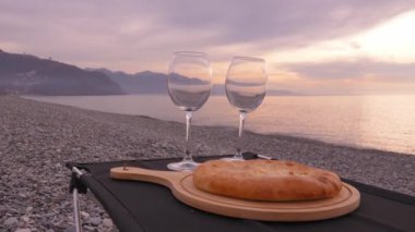 Masada iki tane boş bardak ve güzel dağ ve denizin arka planına karşı khachapuri ya da kubdari peyniri. Gürcü yemekleriyle dolu Gürcistan kıyıları. Sahilde iki kişilik romantik piknik..