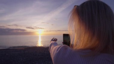 Arka plan, gün batımında cep telefonu tutan kadın elleri. Sunset 'te 
