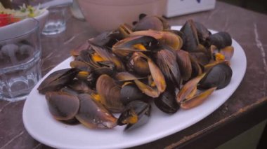 Tahta masada beyaz tabakta midye pişirdim. Bir kase midyeyle resim yapmak. Deniz ürünleri restoran menüleri için mükemmel.