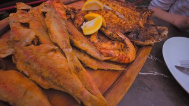 Öğle yemeği için iştah açıcı deniz ürünleri, kırmızı kefal balığı, levrek ve limonlu ızgara fıskiyeler, restorandaki masada. Farklı BBBQ Akdeniz Izgara Yemekleri Yaz BBBQ Diyeti