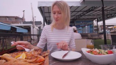 Restoranda balık yiyen kız deniz ürünleri lokantasında fırında levrek yiyen mutlu kadın. Akdeniz diyeti, Gürcistan 'da Batumi' de balık restoranında..