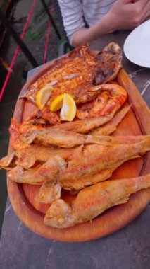 Öğle yemeği için iştah açıcı deniz ürünleri, kırmızı kefal balığı, levrek ve limonlu ızgara fıskiyeler, restorandaki masada. Değişik BBBQ Akdeniz Izgara Yemekleri Yaz BBQ Diyeti. dikey video