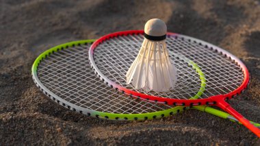 Açık bir badminton kortunun kumunda iki raketi yakın plan çekiyoruz. Aktif eğlence ve eğlence sporları kavramı.