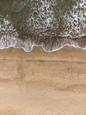 Güneşli bir günde kumlu sahil ve deniz dalgalarının drone görüntüsü. Havadan gelen yaz deniz manzarası. Seyahat kavramı ve fikri