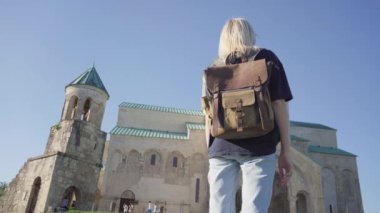 Gürcistan 'ın Kutaisi kentindeki büyük Hıristiyan Bagrat Katedrali' nin önünde sırt çantalı bir kadın turist duruyor. Yürüyüş ve seyahat konsepti .