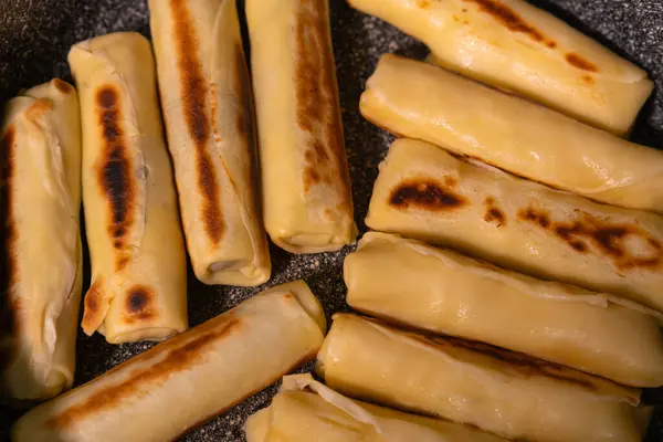 stock image Close-up of delicious mouth-watering pancakes with stuffing fried in a frying pan