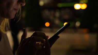 Karanlıkta elinde cep telefonu olan bir kadının sosyal ağlara mesajlar göndermesi, internetten alışveriş yapması, mesaj göndermesi..