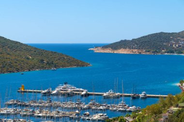 Güneşli bir günde Türkiye 'de Kas yakınlarında yatları olan bir Marina. Yatları, dağları olan güzel bir manzara.