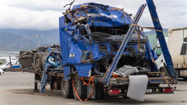 Close up dented blue truck cab and a semi-trailer on a tow platform in the parking lot after a serious accident. clipart