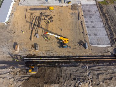 Deniz kıyısında inşaat çalışmaları var. Ağır makineler, temeli su ve fırtına dalgalarından güçlendirmek için çalışıyor. İnsansız hava aracından görüntüle.