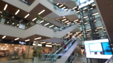 Bulanık görüntüler, alışveriş merkezlerinde yürüyen merdivenlere binen müşterileri ve banliyö sakinlerini yakalıyor.