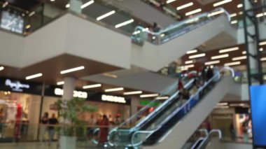 Bulanık görüntüler, alışveriş merkezlerinde yürüyen merdivenlere binen müşterileri ve banliyö sakinlerini yakalıyor.