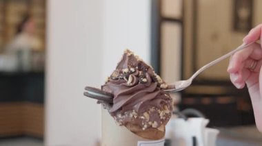 Dondurma ya da trdelnik 'e yakın çekim. Kadın kremasız tatlı kaşığı alıyor. Kafe ya da restoranın içi.