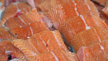 Taze somon filetoları balık pazarındaki buz yatağında dinleniyor. Satılığa hazır, bu canlı filetolar çekici renklerini ve mevcut deniz ürünlerinin kalitesini gösteriyor