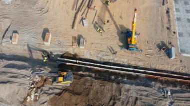 Batumi, Gürcistan - 5 Temmuz 2024: İnşaat işçileri güneşli gökyüzünün altına derin siper destekleme sistemi kurdular. Kazı makineleri ve vinçler de dahil olmak üzere ağır makineler, inşaat sahası projesini destekliyor