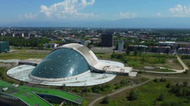 Kutaisi 'nin modern mimarisine aşinayım. Parlamento binasının havadan görünüşü var. Bu sembolik simge şehrin cam cephesinin arka planında göze çarpıyor..