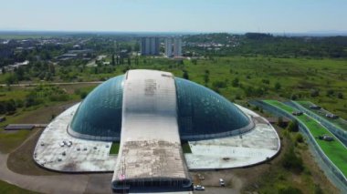 Kutaisi 'nin modern mimarisine aşinayım. Parlamento binasının havadan görünüşü var. Bu sembolik simge şehrin cam cephesinin arka planında göze çarpıyor..