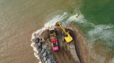 Kazıcı ve çöp kamyonu göl ya da deniz kıyısında. Çöp kamyonu toprağa toprak dökerek set ya da yapay kıyı oluşturur. BAtumi, Georgia.