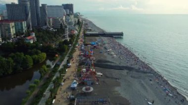 Turistler küçük eğlence parkı olan çakıl taşı plajında gezinirler. Göl ve yemyeşil bitki örtüsü onu modern şehirden ayırır. Yunanistan 'ın sahil beldesi Batumi.