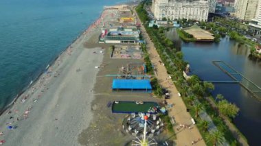 Eğlence parkı gezileri kalabalık plajda yavaşça dönüyor ve turistler Gürcistan 'ın Batumi tatil beldesinde deniz kenarındaki güneşli yaz havasının keyfini çıkarıyorlar. Gezinti.