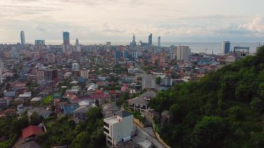 Gürcistan 'daki Batumi' nin canlı şehir manzarası, güneşli gökyüzünün altında modern apartman ve binaların karışımını gösteriyor..