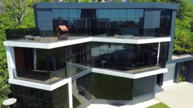 Şatafatlı modern cam ev yeşil orman mahallesine kurulmuş, doğa ve çağdaş mimari arasında çarpıcı bir kontrast sunuyor.