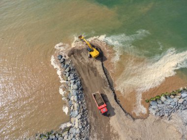 Kum kamyonlu kazıcılar deniz kıyısında, nehirde ya da barajda çalışıyorlar..