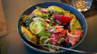 Domatesli, salatalıklı ve maydanozlu taze salata, fındık sosuyla serpiştirilmiş, restorandaki masada güzelce düzenleniyor, yemeğin parlak ve sağlıklı versiyonunu sergiliyor. Gürcistan mutfağı.